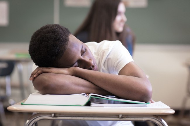 student-sleeping-on-books